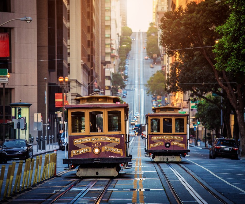 Classic view of historic traditional Cable Cars riding on famous California Street in morning light at sunrise with retro vintage style cross processing filter effect, San Francisco, California, USA