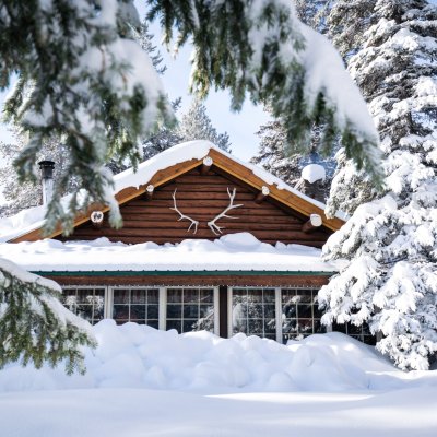 A cozy cabin in the woods, surrounded by snow.