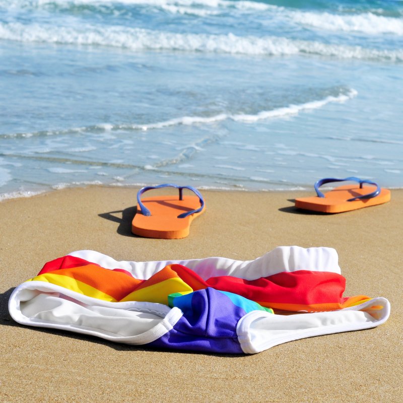 A pair of flip flops and discarded swim suit on a nude beach.