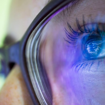 close-up person's eyes in glasses reflecting computer screen