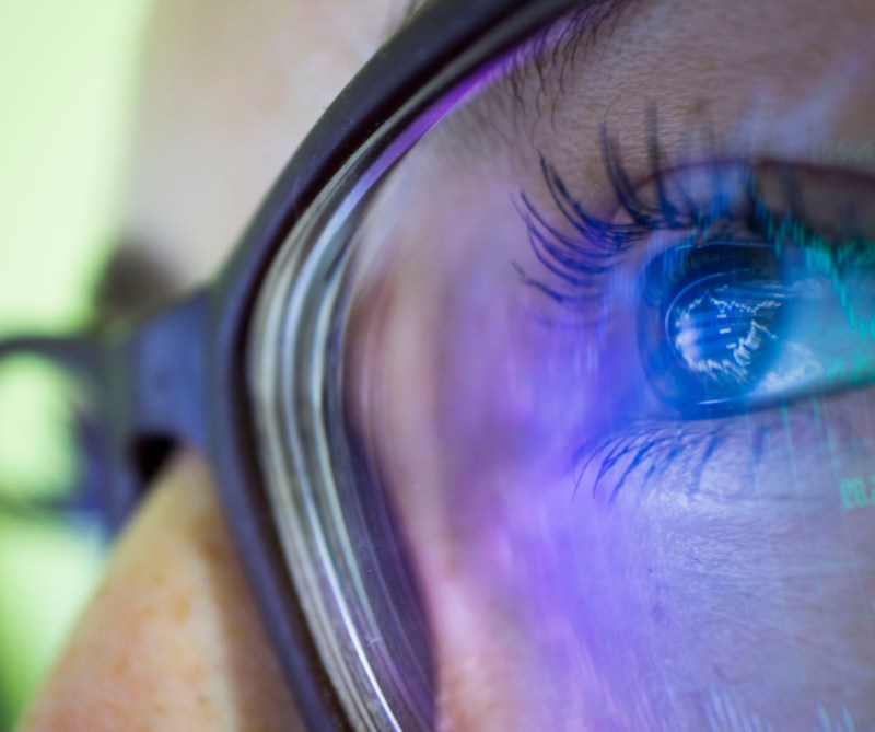 close-up person's eyes in glasses reflecting computer screen