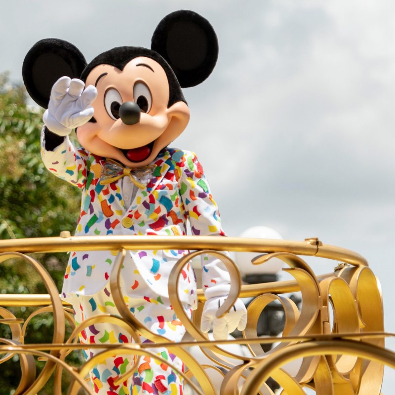 Mickey Mouse waving to visitors at the Magic Kingdom.