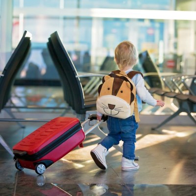 small child walking with backpack and suitcase