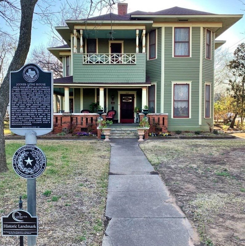 The sidewalk leading to a green historic home.