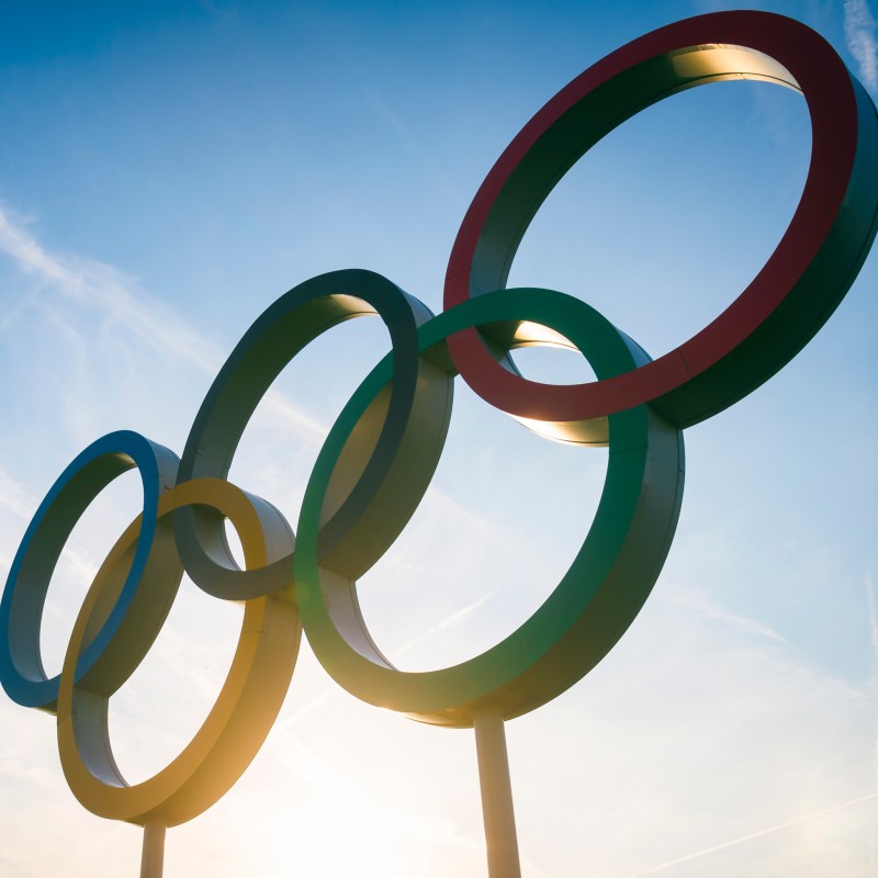 The sun shining behind the Olympic rings.