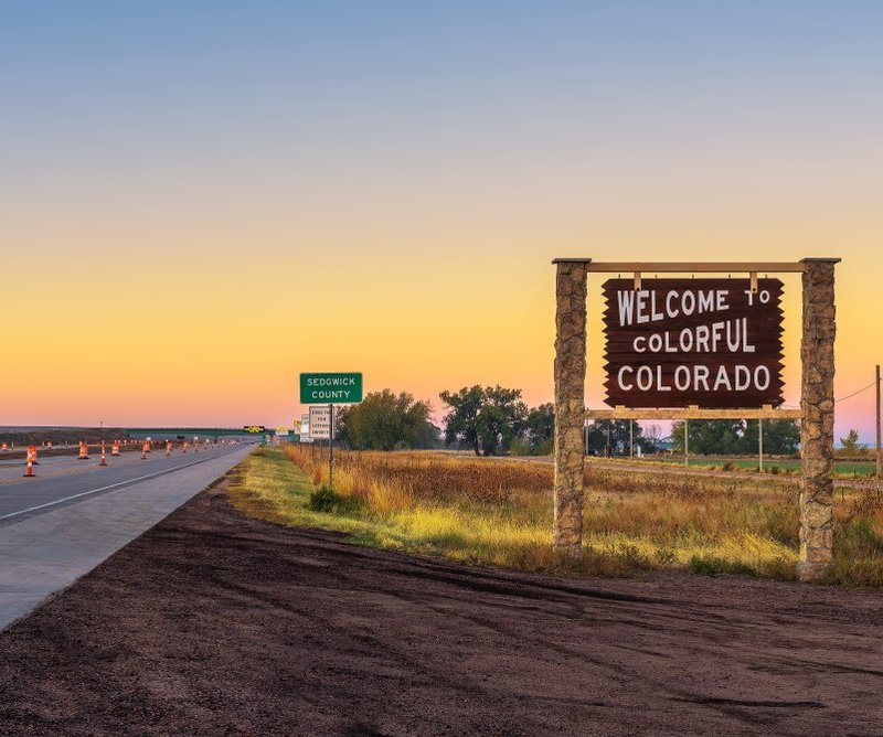 Welcome to Colorful Colorado sign in front of sunset