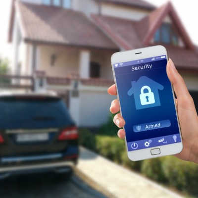 Smartphone with home security app in a hand on the building background