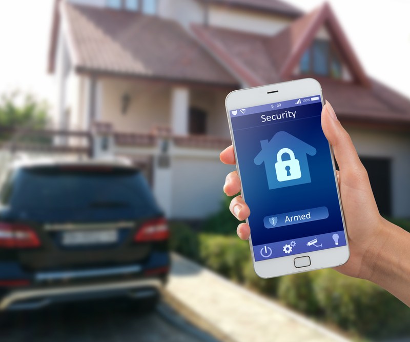 Smartphone with home security app in a hand on the building background