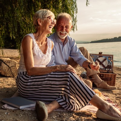 happy woman and man couple over aged 50 picnic by river