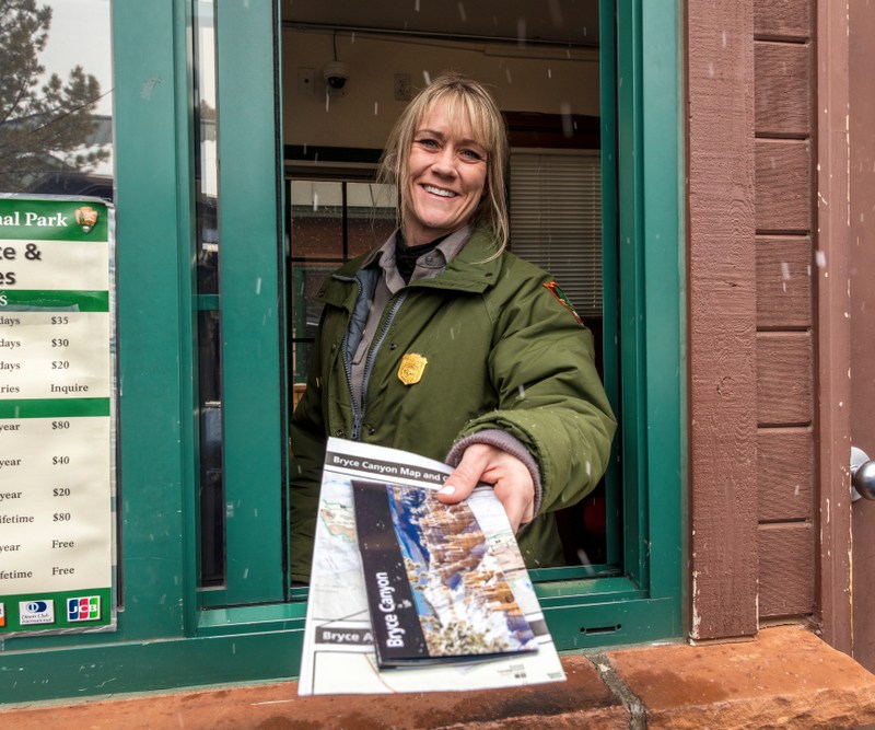 Female blond National Park Ranger hands out brochure through window at Bryce National Park, Utah