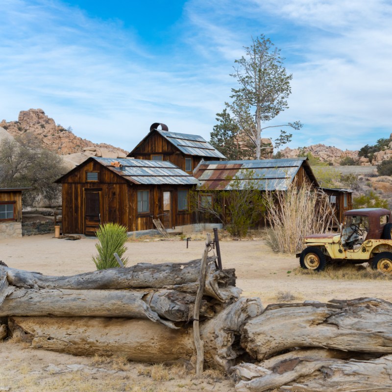 The wooden Key's Ranch house with offroad vehicle towing a trailer in front at Joshua Tree National Park.
