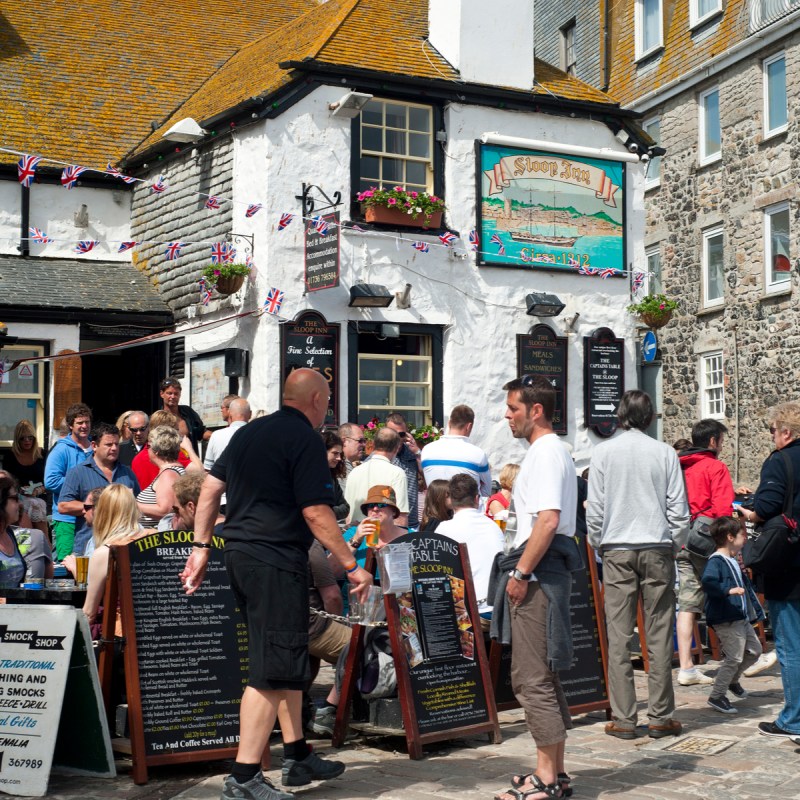 The Sloop Inn traditional 14th century pub busy with holidaymakers sitting outside.