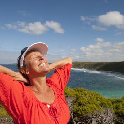 happy middle aged woman on cliff overlooking ocean