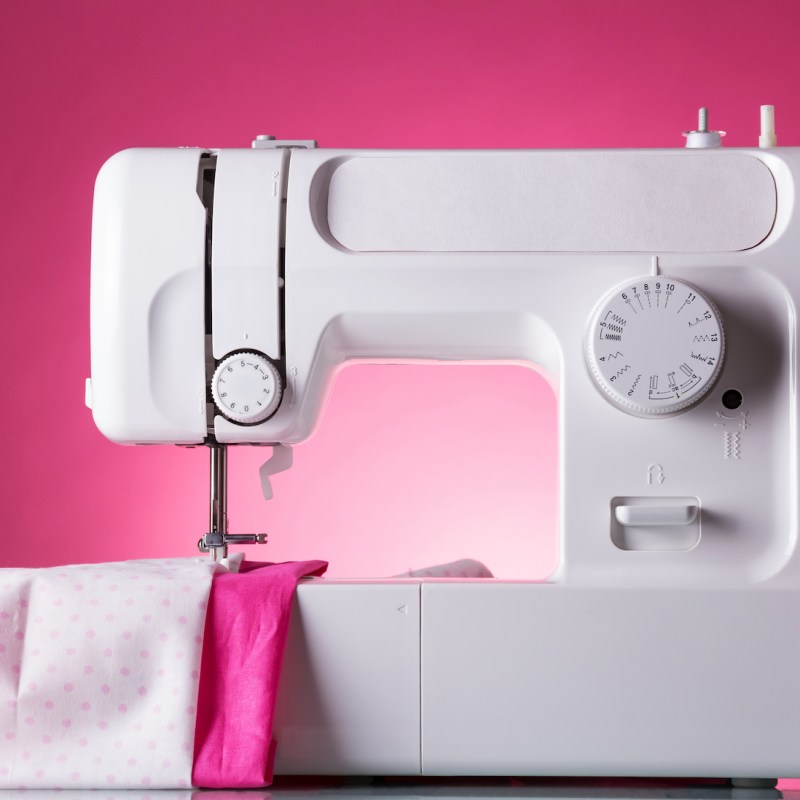 Multifunctional sewing machine, fabric under presser, on pink