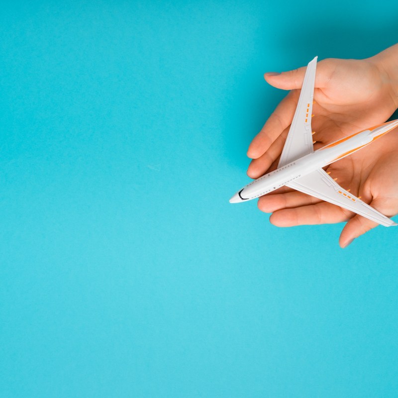 Hand carefully holding model plane. Airplane on blue color background. Security concept