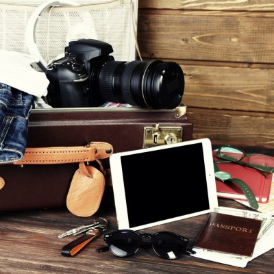 Packed suitcase of vacation items on wooden background