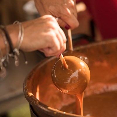 Apple being dipped into caramel.