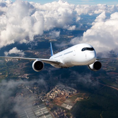 A passenger plane flying high in the clouds. The aircraft flies over the city landscape.