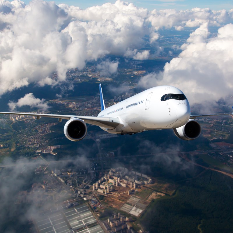 A passenger plane flying high in the clouds. The aircraft flies over the city landscape.