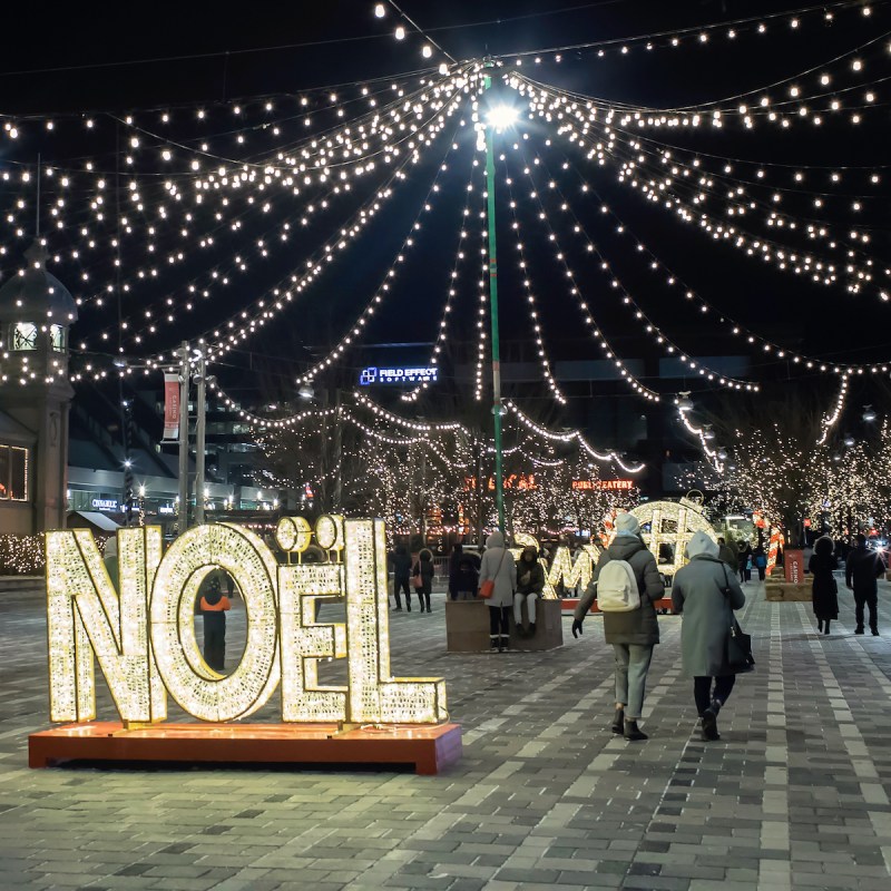 At the Ottawa Christmas Market, a sign reading "Noel" is lit up at night.