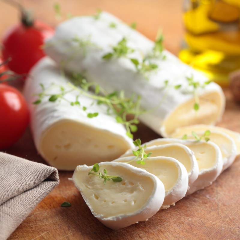 Goat cheese, cherry tomato, and thyme on a wooden cutting board