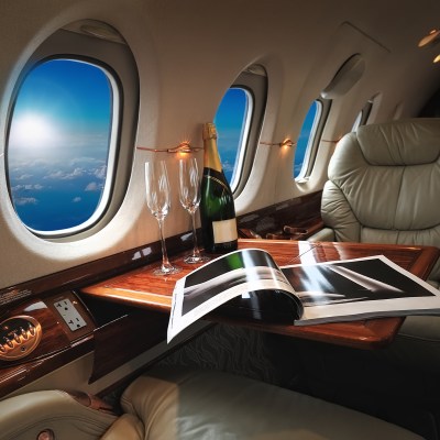 luxury interior in the modern business jet and sunlight at the window/sky and clouds through the porthole