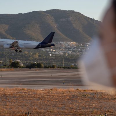 woman wearing N95 mask in front of airplane taking off