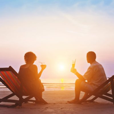 Middle-aged couple relaxing on beach during sunset while snowbirding