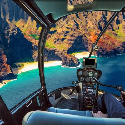 Helicopter cockpit flies in Na Pali coast, Kauai, Hawaii, United States, with pilot arm and control board inside the cabin.