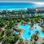 Aerial view of pool, palm trees, and blue and gulf at Sterling Shores Condo in Destin, FL