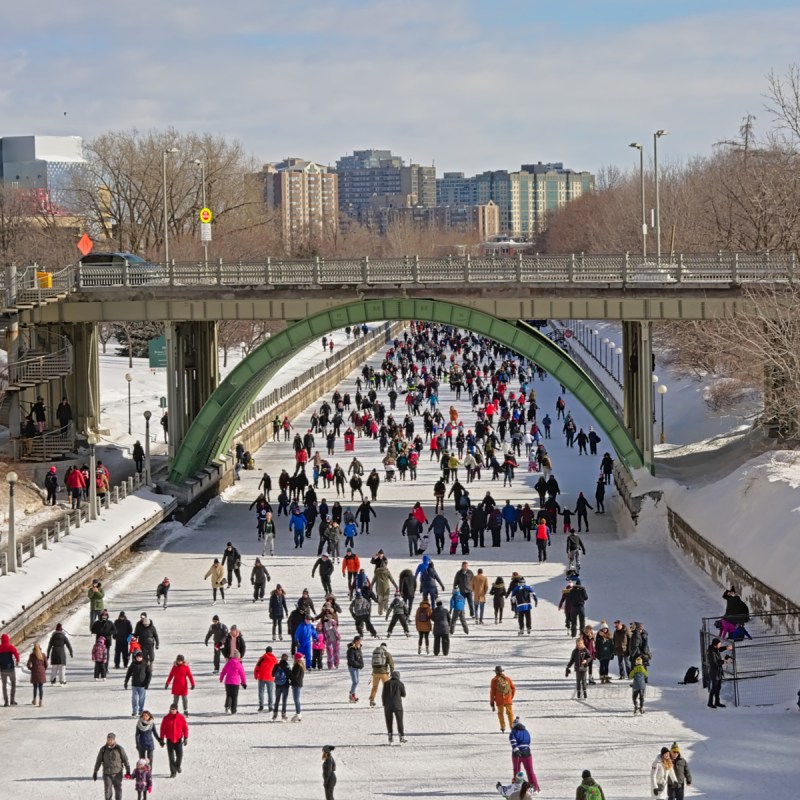 Many people ice skating on the frozen rideau canal on a cold winter day during the winterlude festival.