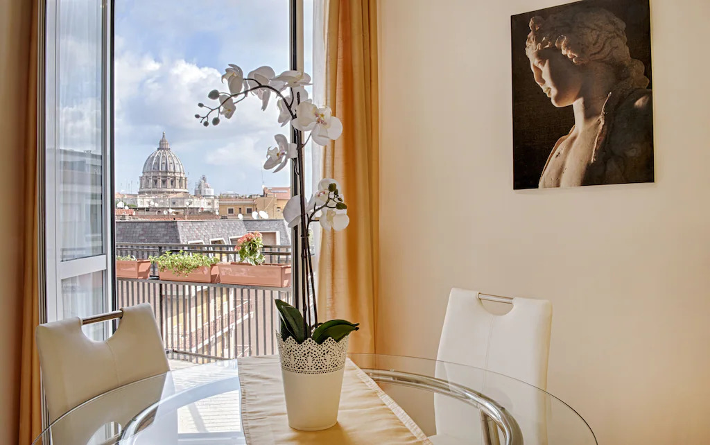 White orchid on glass table in front of window with view of St. Peter’s Basilica