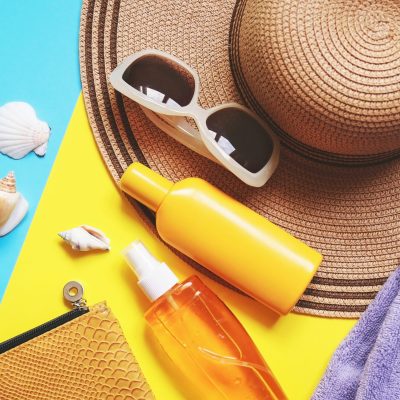 Travel beauty products with beach hat and sunglasses