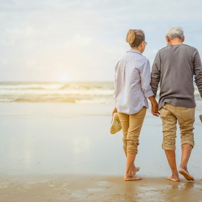 Senior couple walking on the beach holding hands.