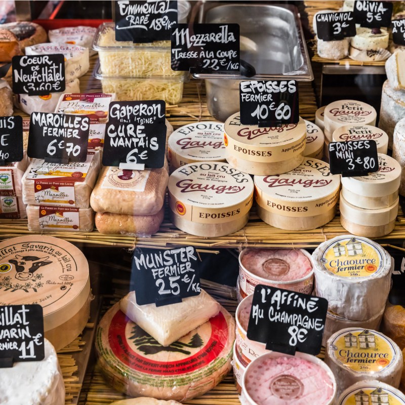 A large selection of different french and italian cheeses on the counter of a small store at the Aligre Market (Marche d'Aligre) in the Bastille district.