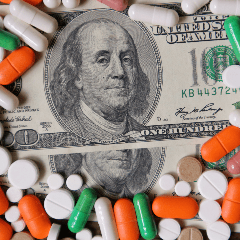 Dollars and pills, a budget for treatment, expensive medications, drug prices in a pharmacy.