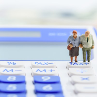 Older american couple stands near a tax button on a calculator