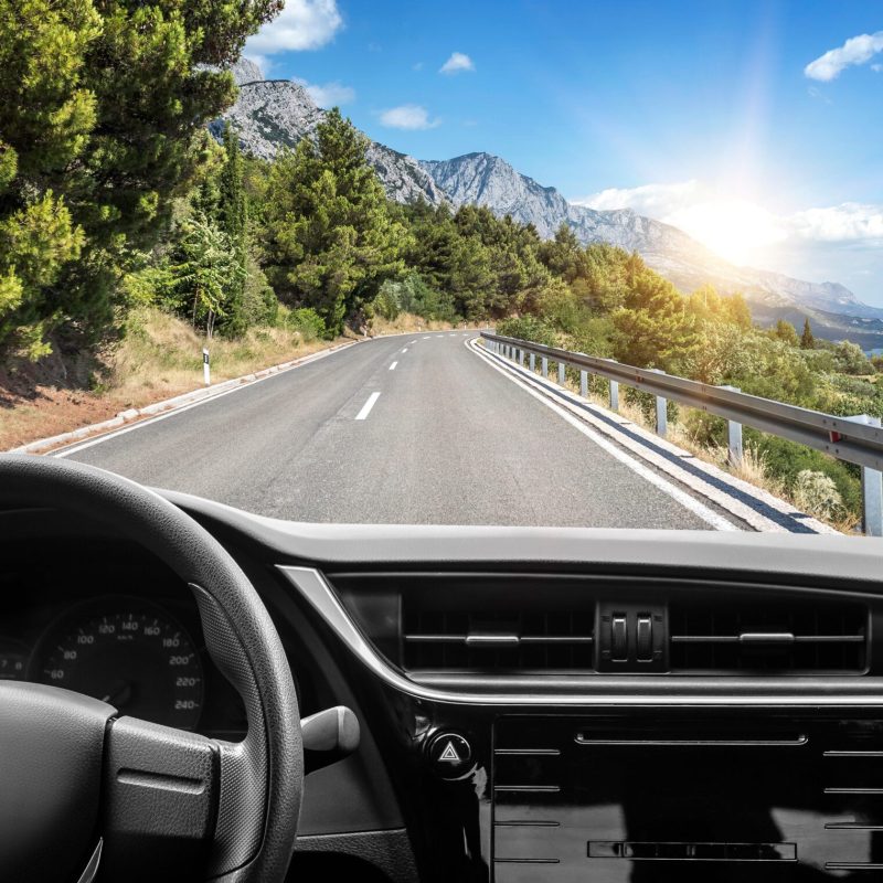 View from driver of car on road trip with ocean and mountains