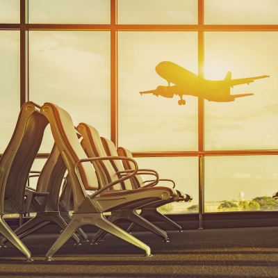 Sunlight coming through the windows of an airport terminal as a plane lands nearby