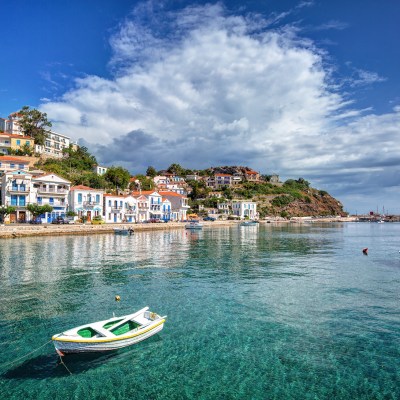 boat floats in blue sea in front of coast of Evdilos village on Ikaria Island, Greece