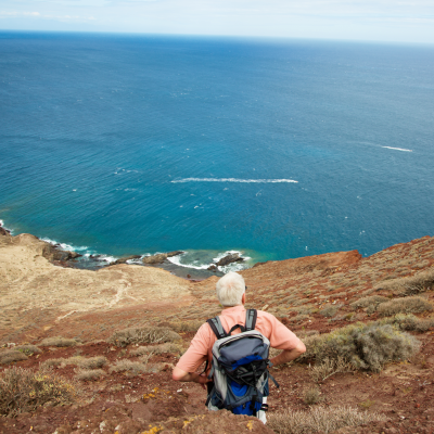 Rear view of elderly man with backpack standing on island edge