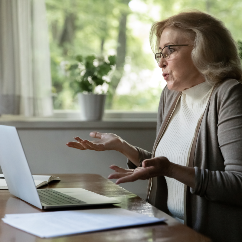 Confused old Caucasian woman work on laptop at home