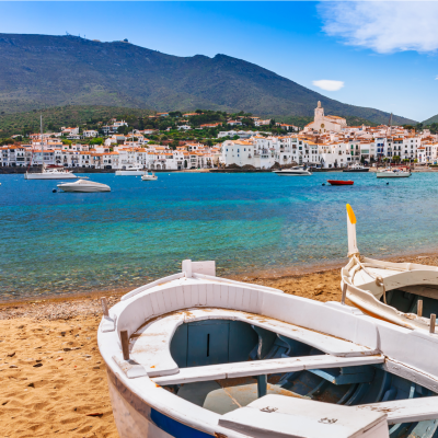 View of Cadaqués, Spain, with high hills in the background and beached boats in the foreground.