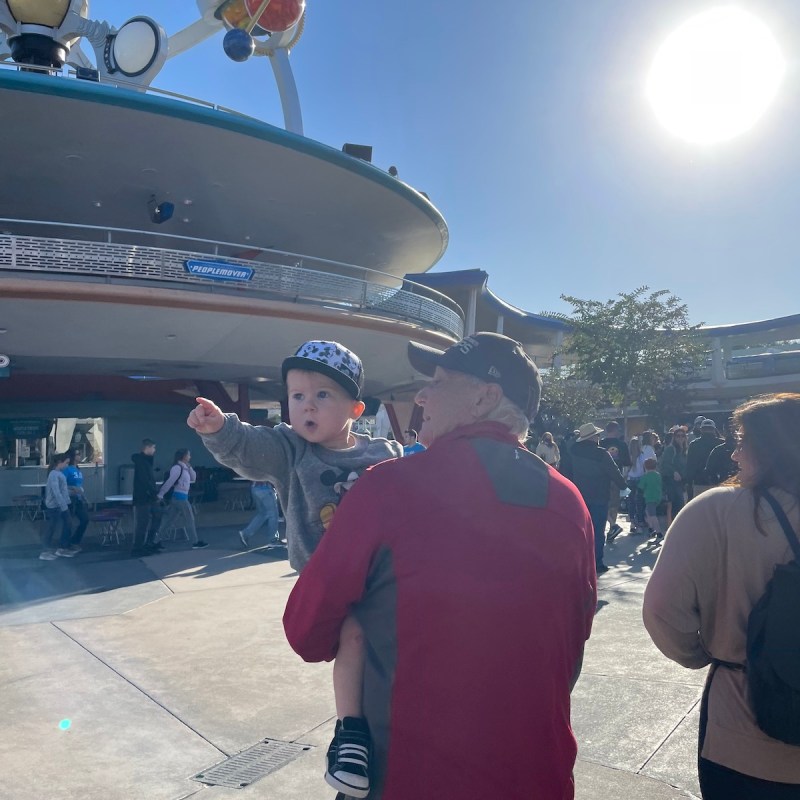 Grandson points while being carried by grandfather Walt Disney World.