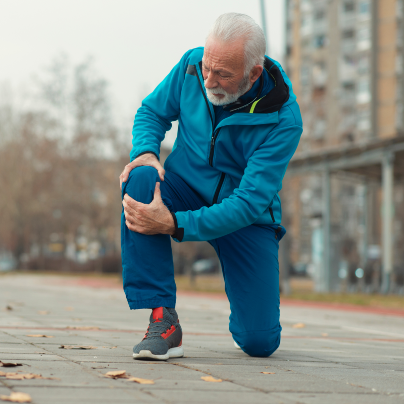 The senior man use hands hold on his knee while running outdoor