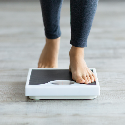 woman stepping on scales to measure her weight at home, closeup of feet