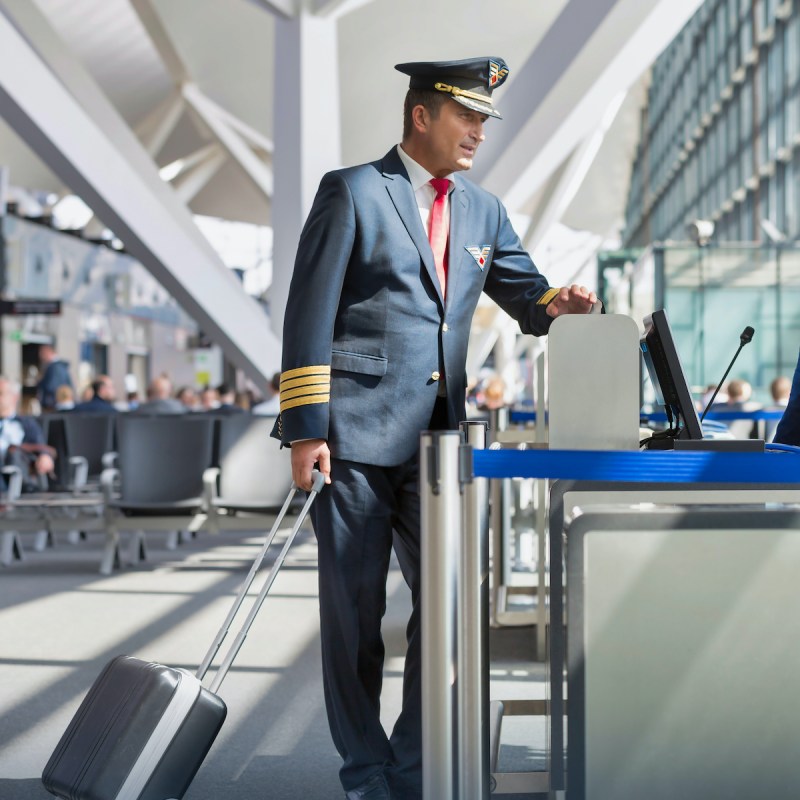 Portrait of mature pilot talking with the airport staffs in boarding gate