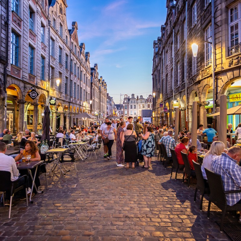 Busy outdoor street cafes at sunset on the cobblestones of Arras, Pas de calai, France