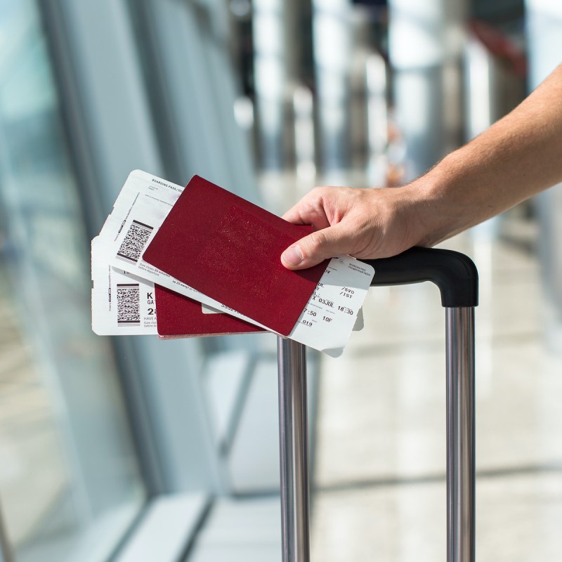 Closeup of man holding passports and boarding pass at airport