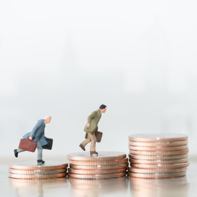 small figures businessmen walking and running on top of coins
